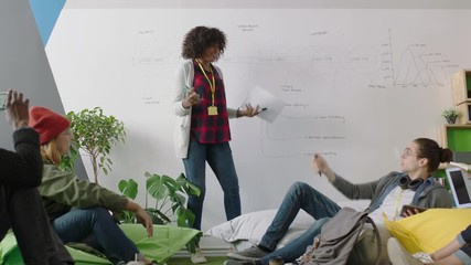 young african american business woman teaching group of students showing project timeline on whiteboard presenting graph data diverse team brainstorming sharing ideas in office lecture