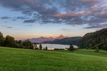 Blick über den Weißensee bei Füssen mit Alpenglühen auf den Bergen im Hintergrund