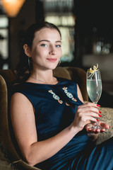 Fashionable gorgeous girl in a dark blue dress drinking cocktail in a luxery hotel lobby bar