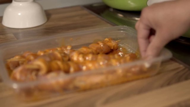 Woman cook cooking chicken skewers frying in pan on gas stove