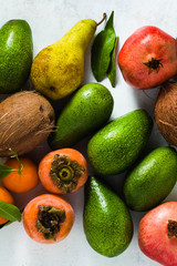 different fruits of pomegranate, pear, mandarin, lemon, avocado and persimmon with coconut on the table. basis of healthy nutrition and daily juices