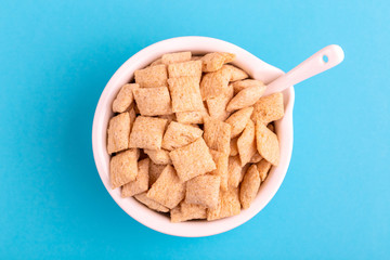 Crunchy corn pads in clay bowl on bright blue background