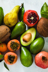 different fruits of pomegranate, pear, mandarin, lemon, avocado and persimmon with coconut on the table. basis of healthy nutrition and daily juices