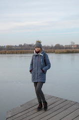 A beautiful smiling girl in a yellow winter jacket, warm hat and boots in the middle of a frozen lake.