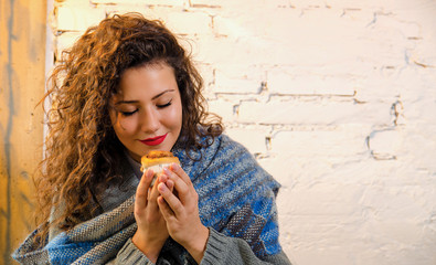 Closeup young woman holding cinnamon roll enjoying the smell of it 