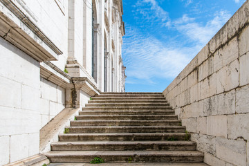 Old white marble steps and marble block walls moving to perspective under a brilliant blue sky in Lisbon, Portugal
