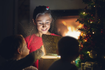 Little girl joyfully smiling as she opens golden gift box