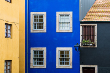 Fototapeta na wymiar Old brightly colored buildings with stucco painted in yellow, blue, and black hues in Porto, Portugal