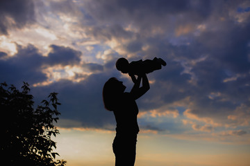 Mother holding a baby on a sky background. Mother and a son. Happy family