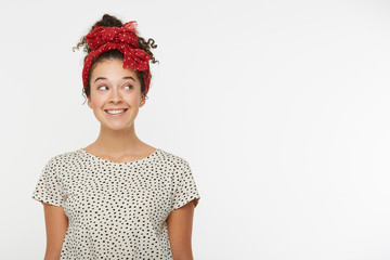 Horizontal portrait of female model looking with interest aside on blank white copy space for your advertisement or promotional text. Lovely girl dressed tshirt with black polka dots