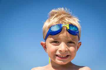 Little Boy Wearing Blue Goggles and Smiling at the Camera