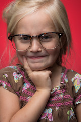 Cute Little Girl Thinking with Glasses on Against a Red Background