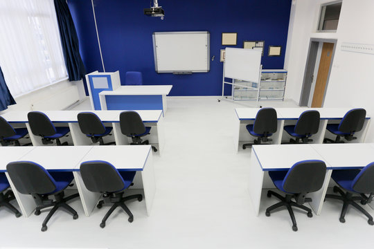 Economy School Classroom With Smart Board And Without Students Or Teacher With Chairs And Tables In Campus. Modern Education Concept.