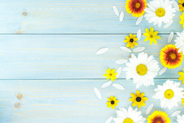 White daisies and garden flowers on a light blue worn wooden table. Empty space on the other side.