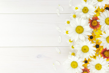 White daisies and garden flowers on a white wooden table. The flowers are arranged side, empty space left on the other side.