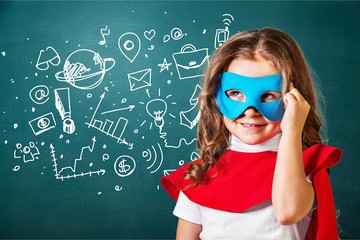 Little cute girl in blue glasses near green blackboard