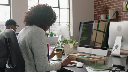 young african american woman programmer coding network security software for startup company professional web developer typing code on computer screen drinking coffee in modern startup office 