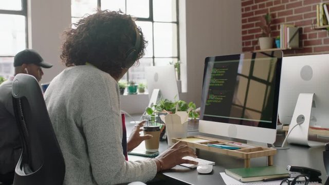 young african american woman programmer coding network security software for startup company professional web developer typing code on computer screen drinking coffee in modern startup office 