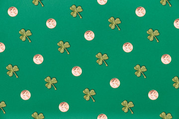 Glitter shamrocks and golden coins on green paper background. St Patricks day symbol. Irish National holiday concept