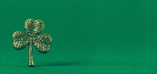 Glitter shamrock on green paper background. St Patricks day symbol. Irish National holiday concept