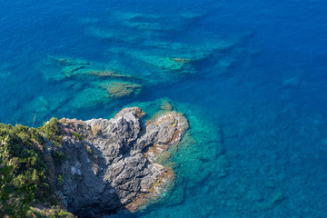 Fototapeta na wymiar Crystal clear water and rocky shore of the Ligurian coastline, as seen from the Cinque Terre trail