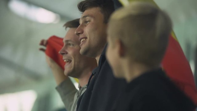 Child And Adult Spanish Football Fans Waving Flag, Singing National Anthem