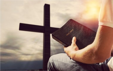 Man reading old Bible book on background