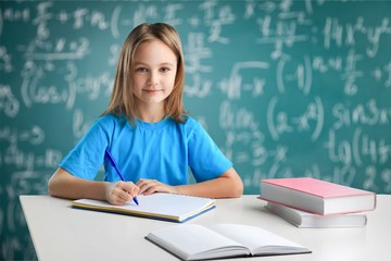 Little schoolgirl with book on chalkboard background