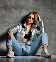 Young sport woman after workout exercise sitting under snow in silver sexy thin down puffer jacket blue jeans © Dmitry Lobanov
