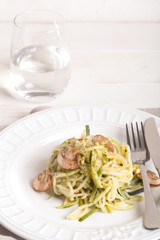Plate of spaghetti prepared from zucchini and mushroom sauce on wooden table