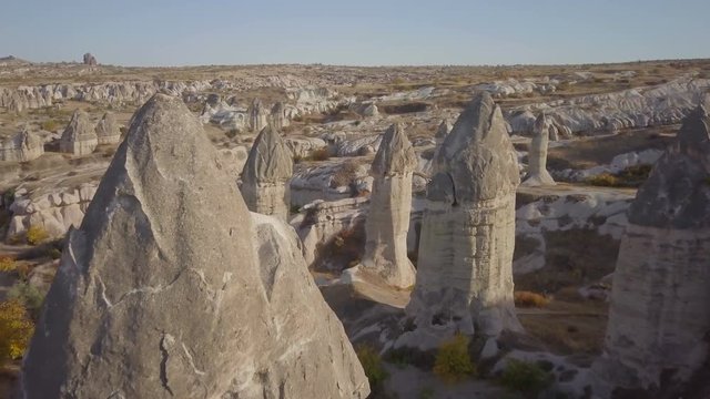 High angle advancing aerial drone view flying near through phallic fairy chimney or hoodoo formations and rocky landscape at daytime in Cappadocia, Turkey. 4k at 23.97fps