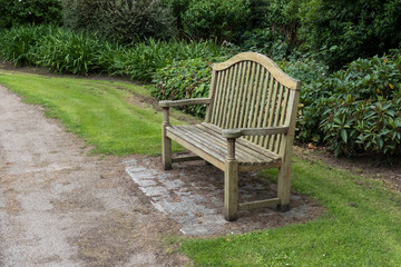 An empty wooden park bench in a public park.
