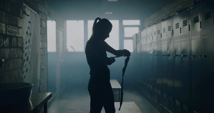 MS Caucasian female wraps her hands in locker room before boxing martial arts training. 4K UHD 60 FPS SLOW MOTION