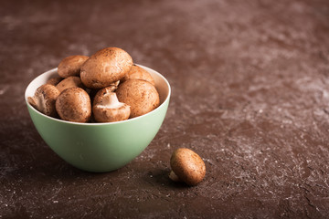 Portabello mushrooms in a green bowl on a dark background