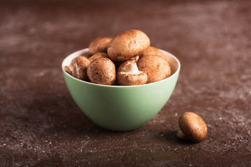 Portabello mushrooms in a green bowl on a dark background