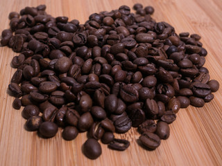 Fresh roasted natural coffee beans close up from above at an angle on natural wood surface