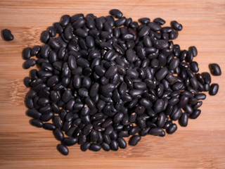Raw Black Beans on a natural wooden surface. Top down overhead view.