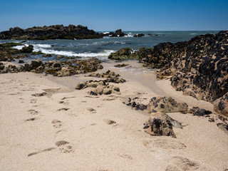 Sunny beach on a summer day in Portugal with golden sand, rocks and Atlantic ocean in background. Povoa de Varzim, Porto.