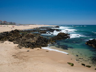 Beautiful sandy / rocky beach in summer, clear blue water and blue cloudless sky in Vila do Conde, Porto, Portugal