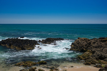 Fototapeta na wymiar Beautiful rocky beach in Portugal, on sunny day with clear blue water and blue cloudless sky. Vila do Conde, Porto region.