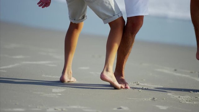 Feet of Hispanic father and son playing with soccer ball on the beach