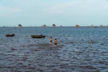 Children playing on shallow water at oyster raising field in Dong Chau beach, Thai Binh, Vietnam