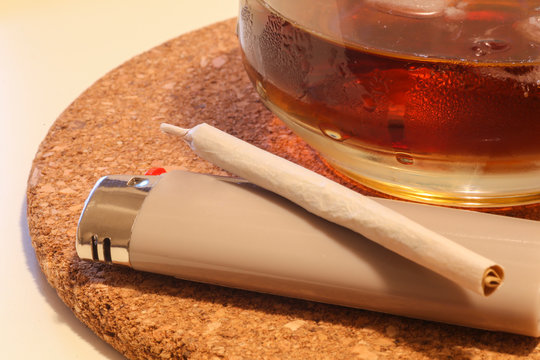 Close-up of a pot cigaret and a drink on the table. Relax time VS Addiction issue
