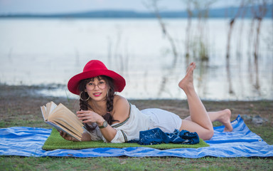 Beautiful woman reading a book near the water.
