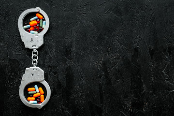 Arrest for illegal purchase, possession and sale drugs concept. Drugs as pills near handcuff on...