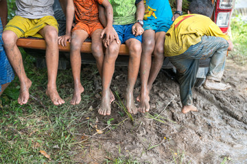 Fototapeta na wymiar Dirty feet with mud of children sitting on a pickup, closeup