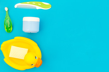 Children's personal care kit. Bath accessories with teeth brush and yellow rubber duck on blue background top view copy space
