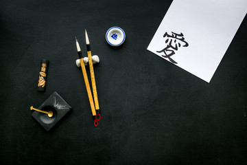 Chinese or japanese calligraphy concept. Hieroglyph near traditional written accessories on black...