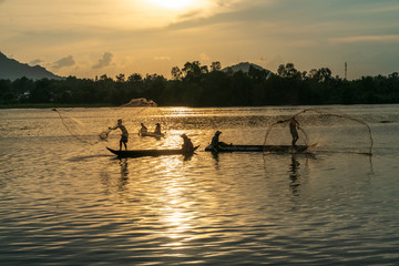 Fisher men fishing on a fishing boat in river in Mekong Delta on floating water season at sunset
