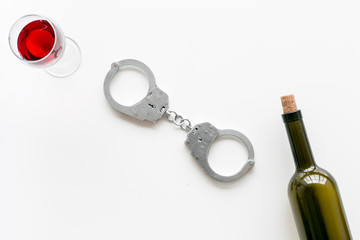 Illegal sale of alcohol concept. Handcuffs near wine glass and bottle on white background top view copy space